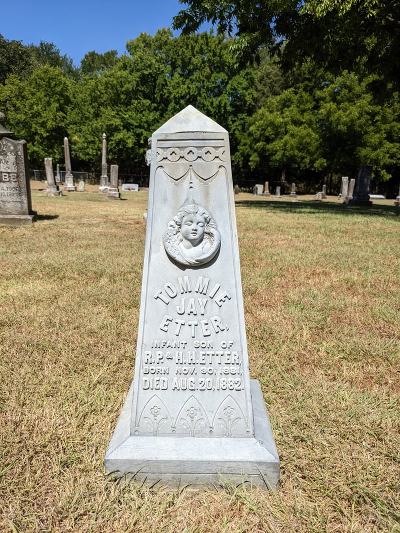 Historic gravestone with carved portrait, raised lettering and decorative floral details